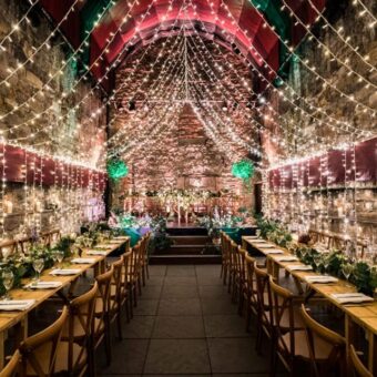 Wooden Trestle Tables Set-Up for Dinner in the Main Vault of The Caves, Edinburgh, with Additional Fairy Lights.